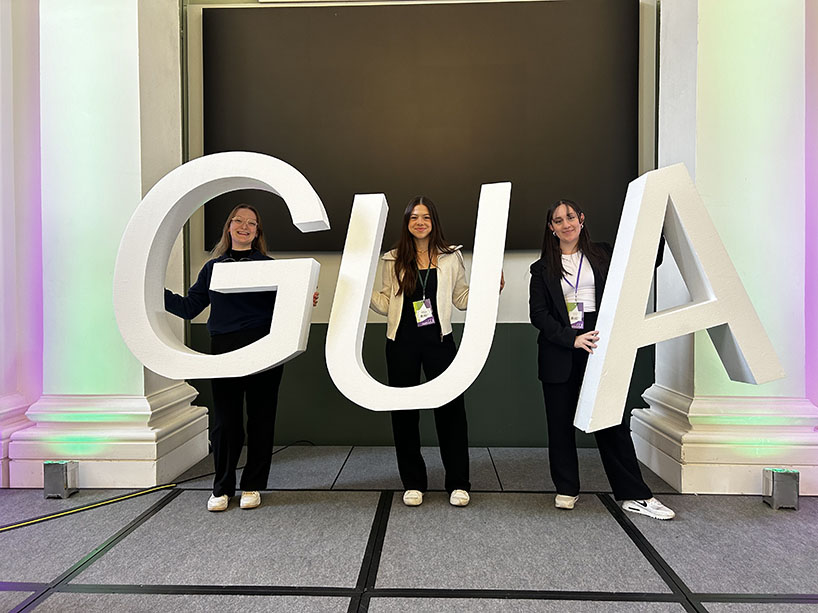 Three award winners individually holding the letters “G”, “U” and “A”, to represent the Global Undergraduate Awards