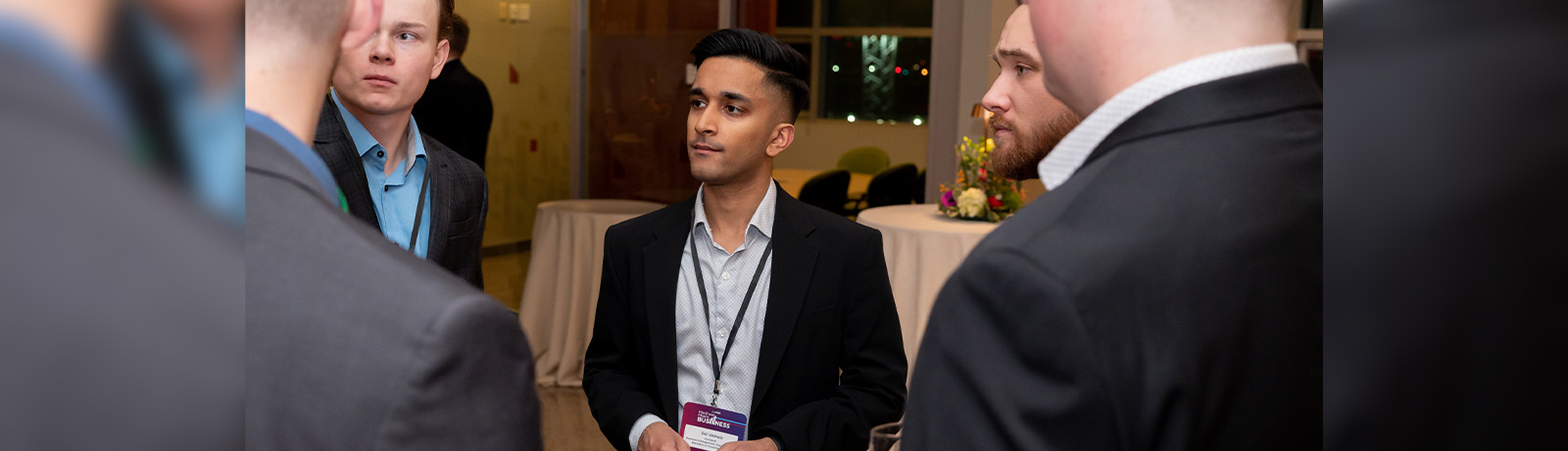 Sid Vemula talks to other guests at an event, wearing a black suit.